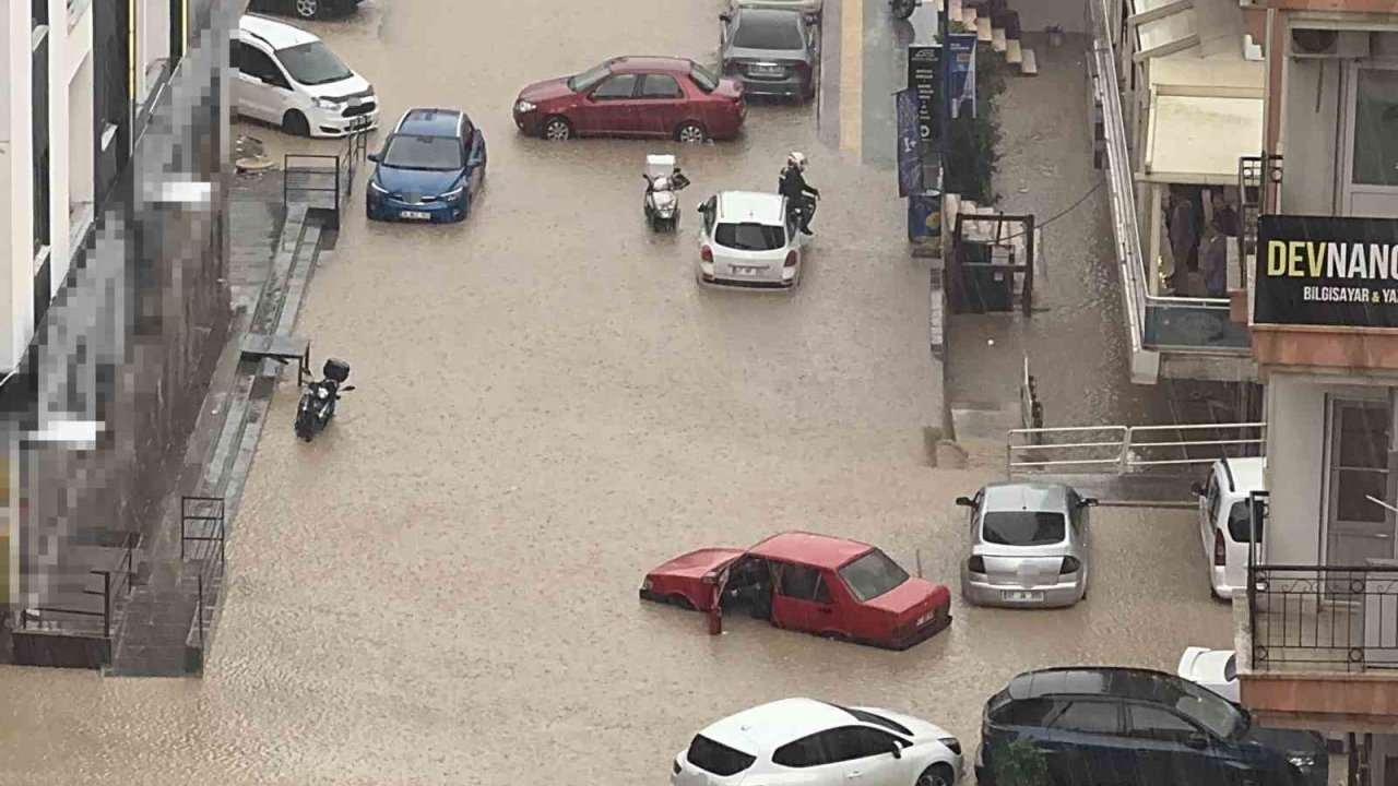 Yağmurda mahsur kalan motosikletli çareyi otomobilin üzerine çıkmakta buldu
