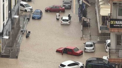 Yağmurda mahsur kalan motosikletli çareyi otomobilin üzerine çıkmakta buldu